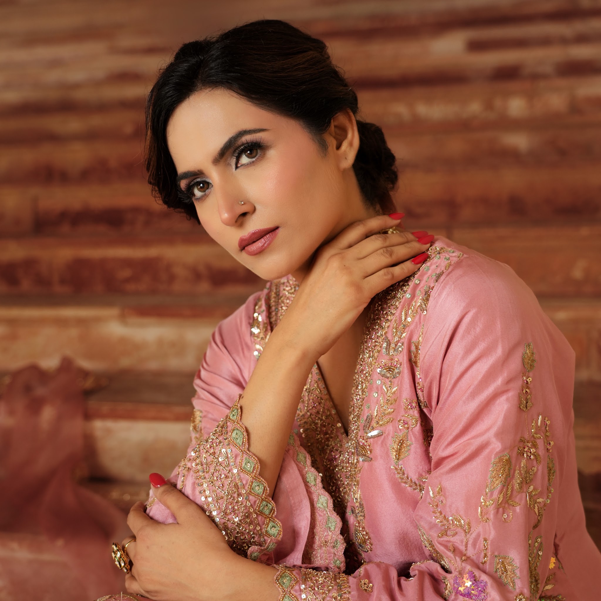 A close portrait of a woman in a pink embroidered outfit